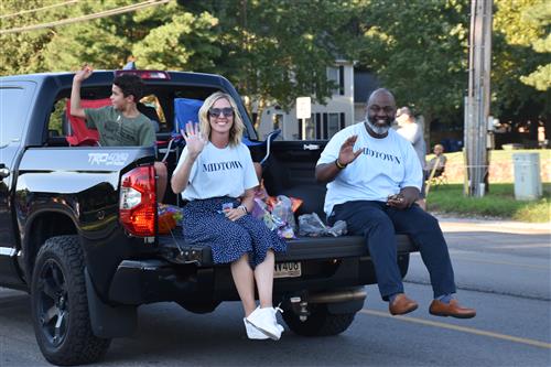 Midtown elementary principal and assistant principal sitting on truck tailgate in parade